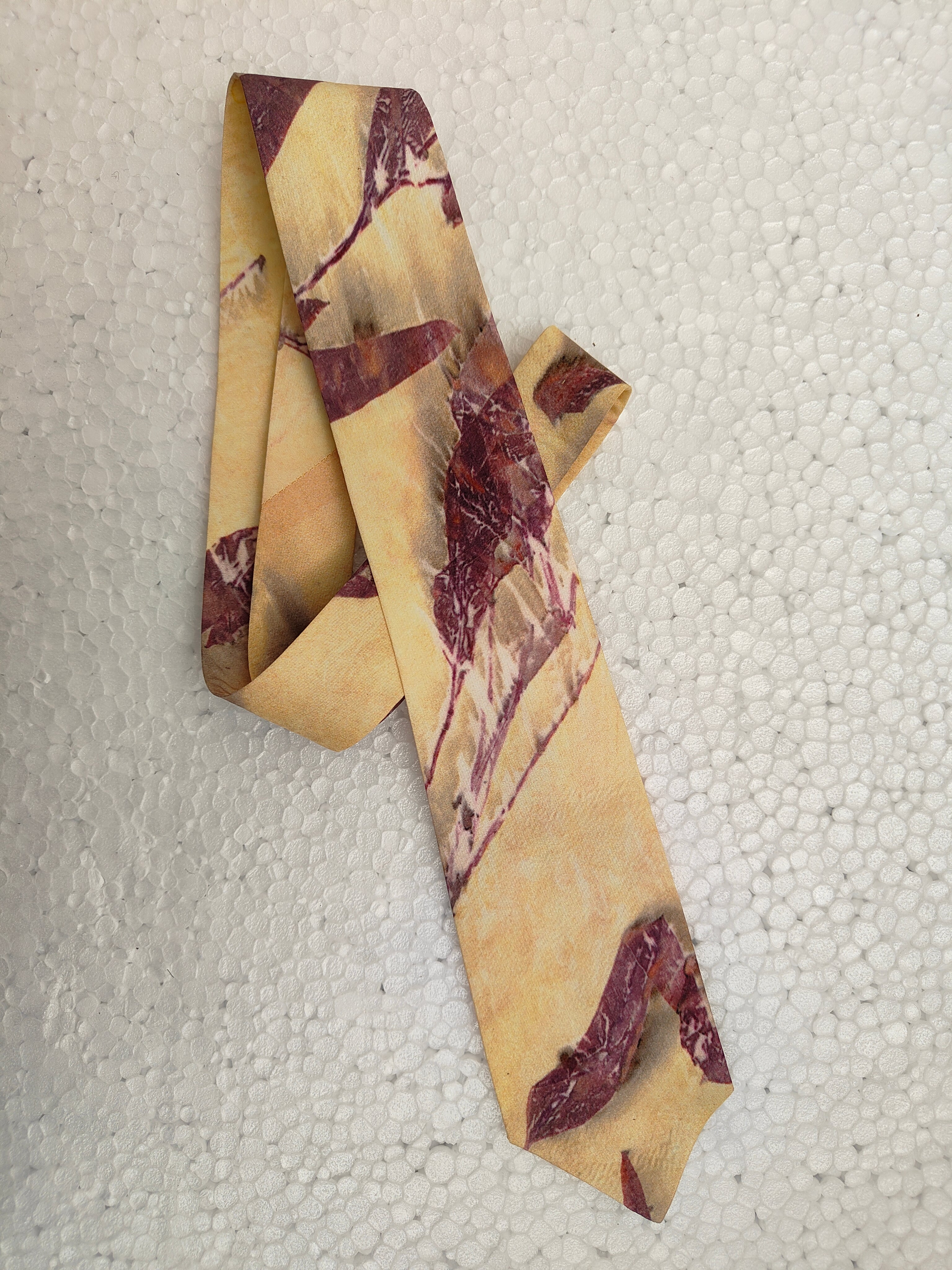 Marbled patterned silk tie on a textured white background