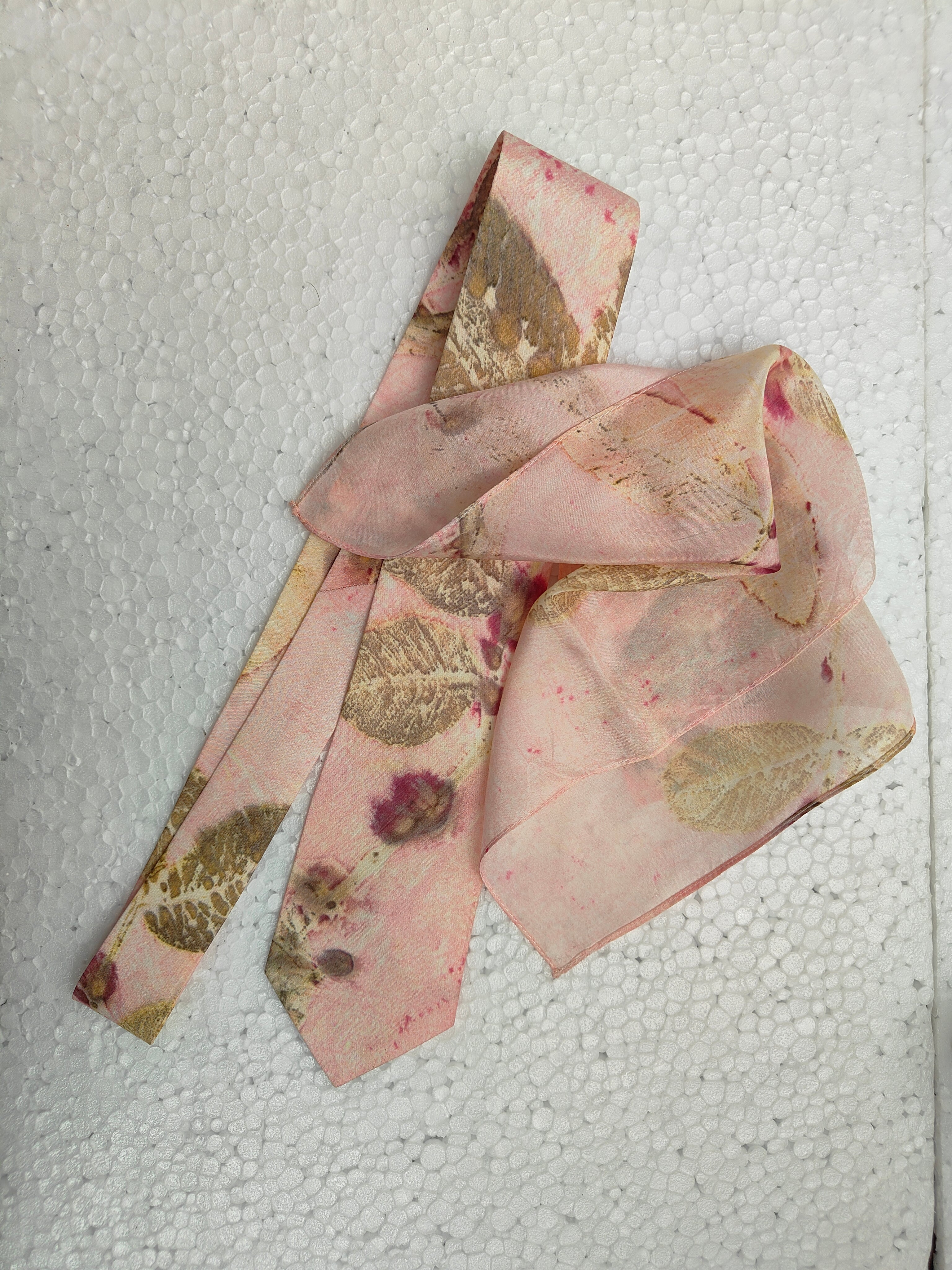 Pink floral silk tie on a textured white background