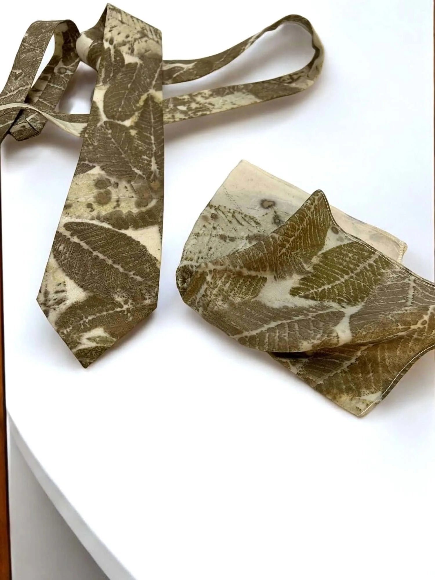 Floral-patterned silk tie and pocket square on a white surface