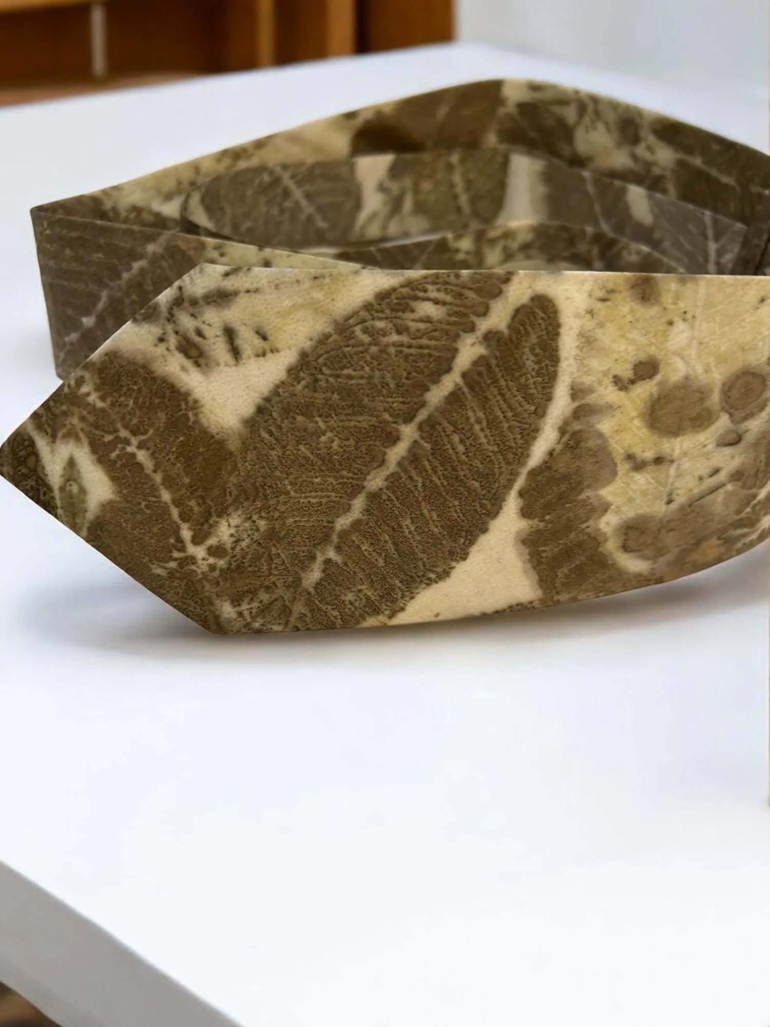 mens silk tie with leaf pattern on a white surface