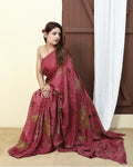 Woman wearing a red pure silk  saree with gold leaf patterns, siting indoors against a neutral background