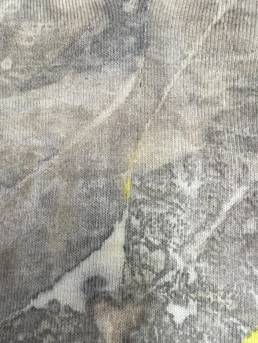 Close-up of textured fabric with a Sustainable cotton socks with leaf print in earthy tones and yellow accents