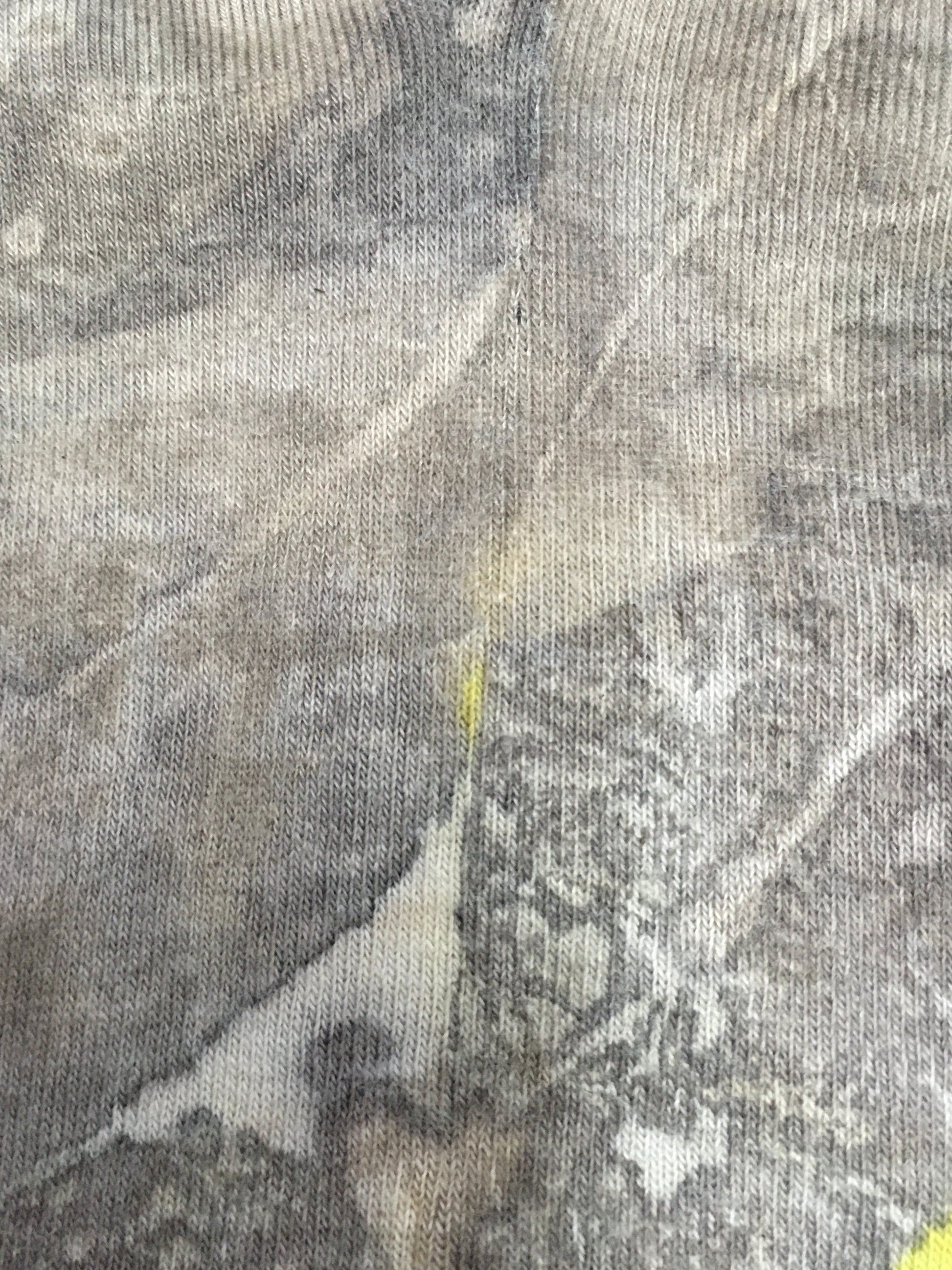 Close-up of textured fabric with a Sustainable cotton socks with leaf print in earthy tones and yellow accents