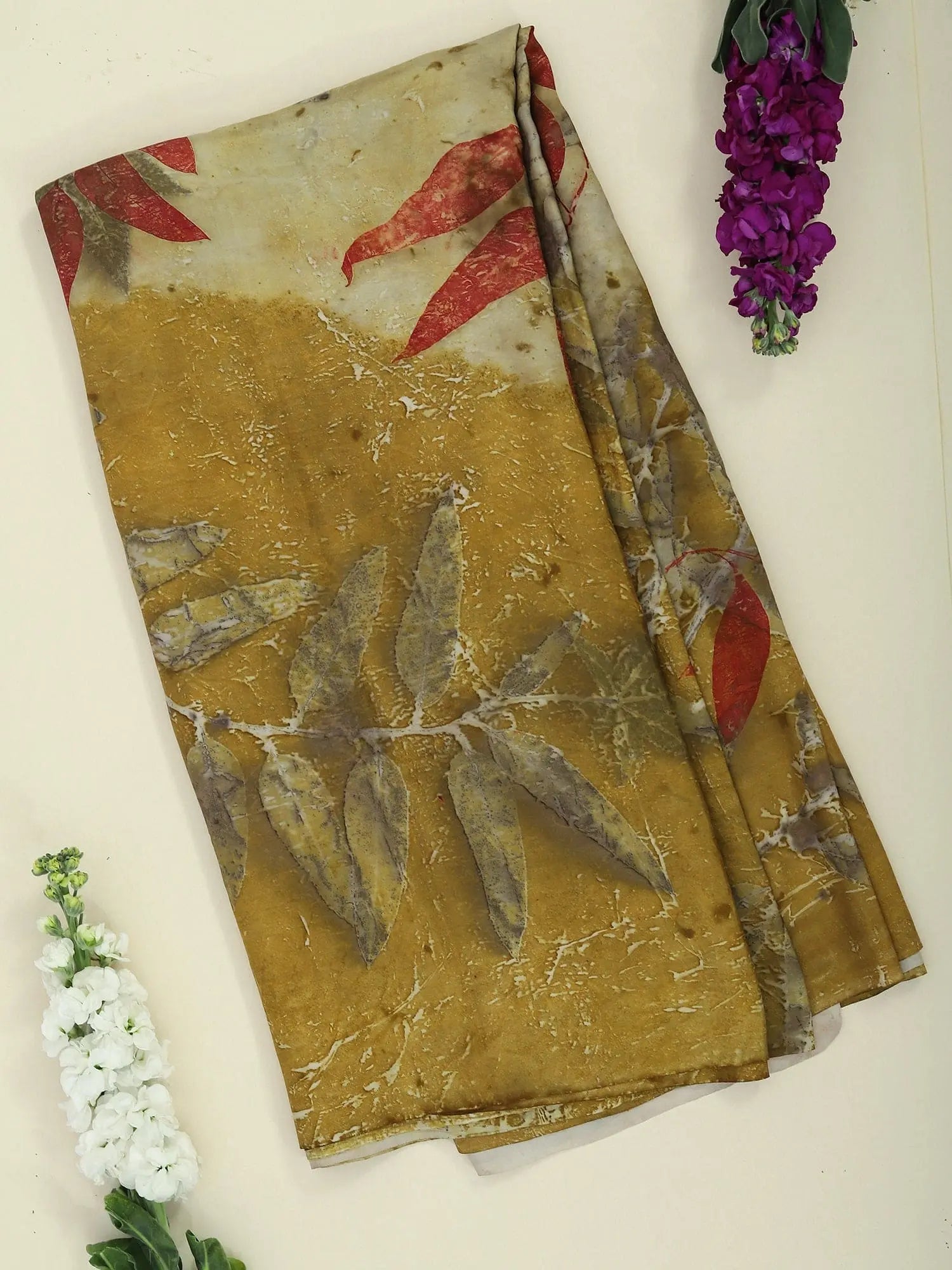 Twilight ecoprinted Pure Silk Saree by kokikar on the floor with two flowers