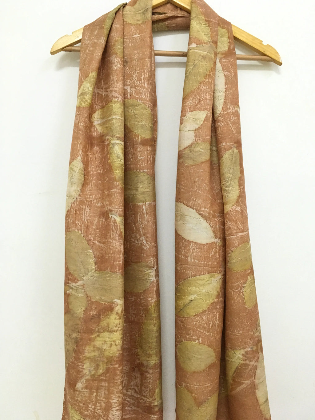 Pure Silk Ecoprinted Scarf with leaf pattern on a wooden hanger against a white background