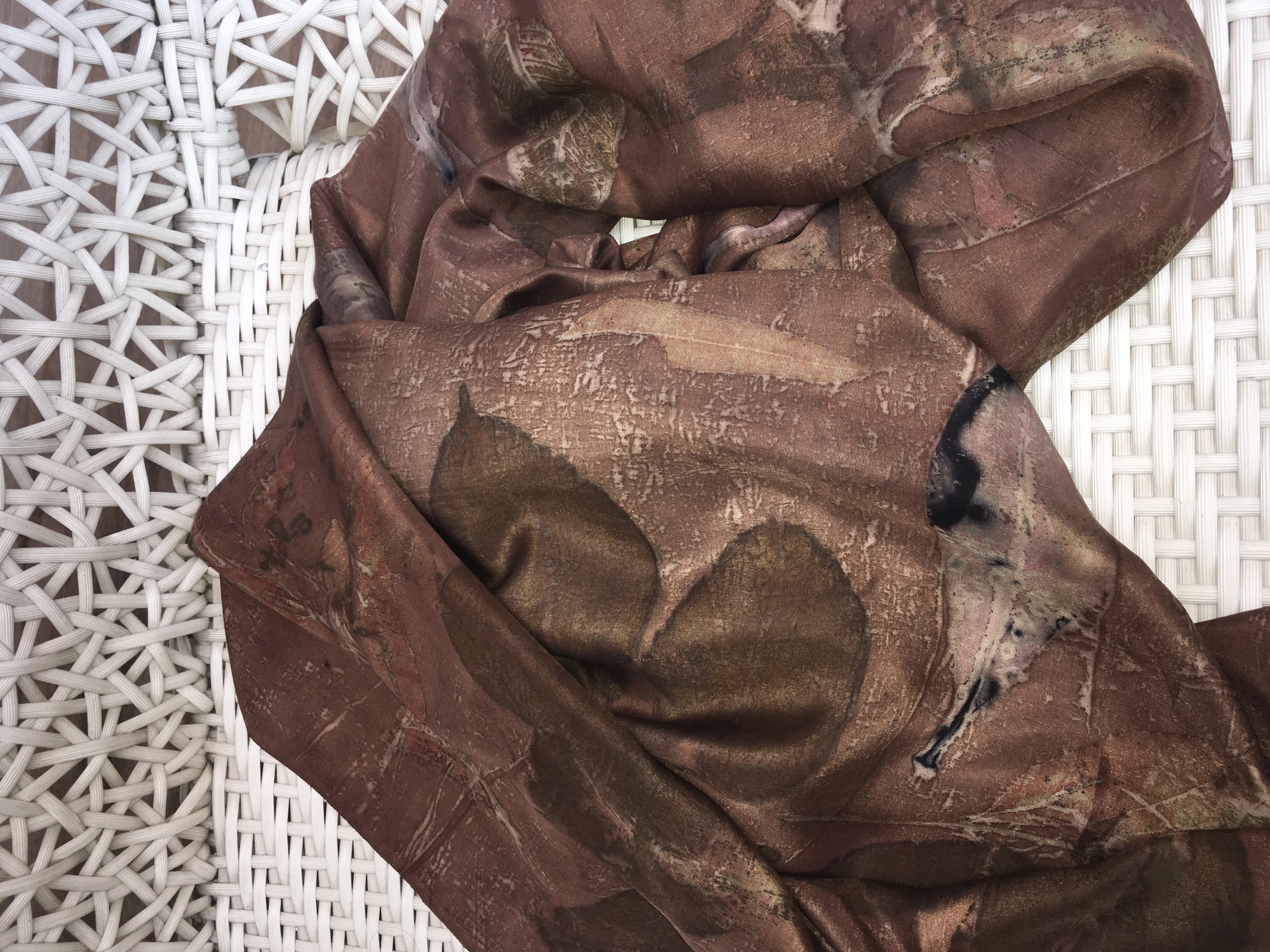 Brown Handmade eco printed silk scarf featuring mixed leaf impressions and natural catechu dye on luxurious pure silk on a textured white surface