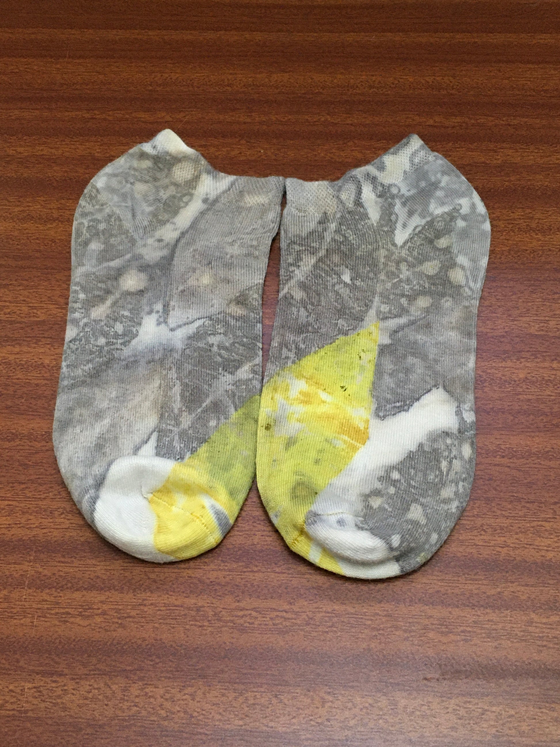 Pair of ecorpinted socks with guava leaves and turmeric (haldi) on a wooden surface