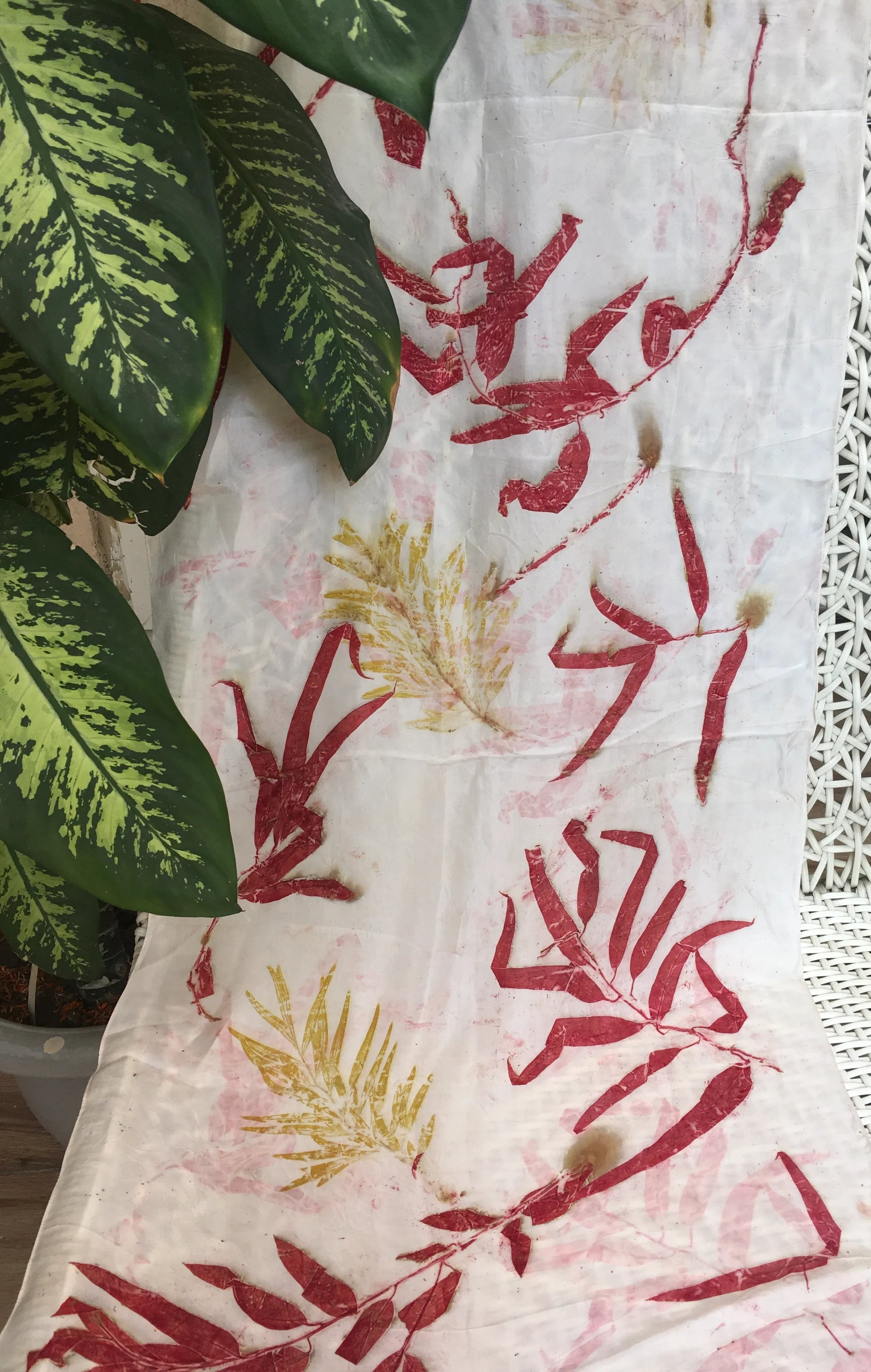 Eco printed pure silk scarf with crimson eucalyptus leaf prints and natural botanical patterns on white silk fabric.