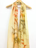 Handcrafted golden pure silk scarf featuring eco-printed eucalyptus leaves in orange, green, and yellow tones created using natural dyes and sustainable botanical printing techniques.