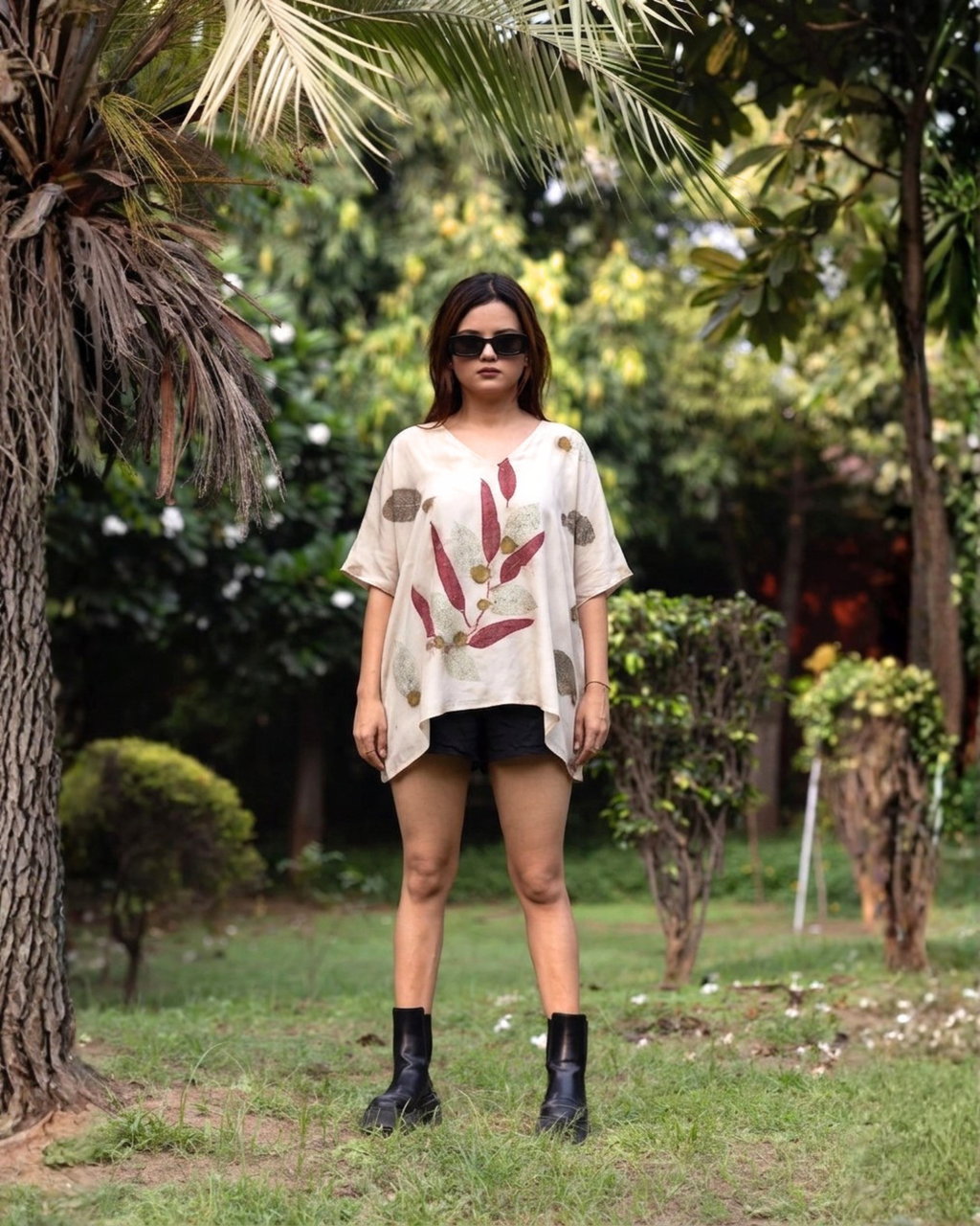 girl wearing a ecoprinted Kaftan Flared Top and black shorts standing in a garden.