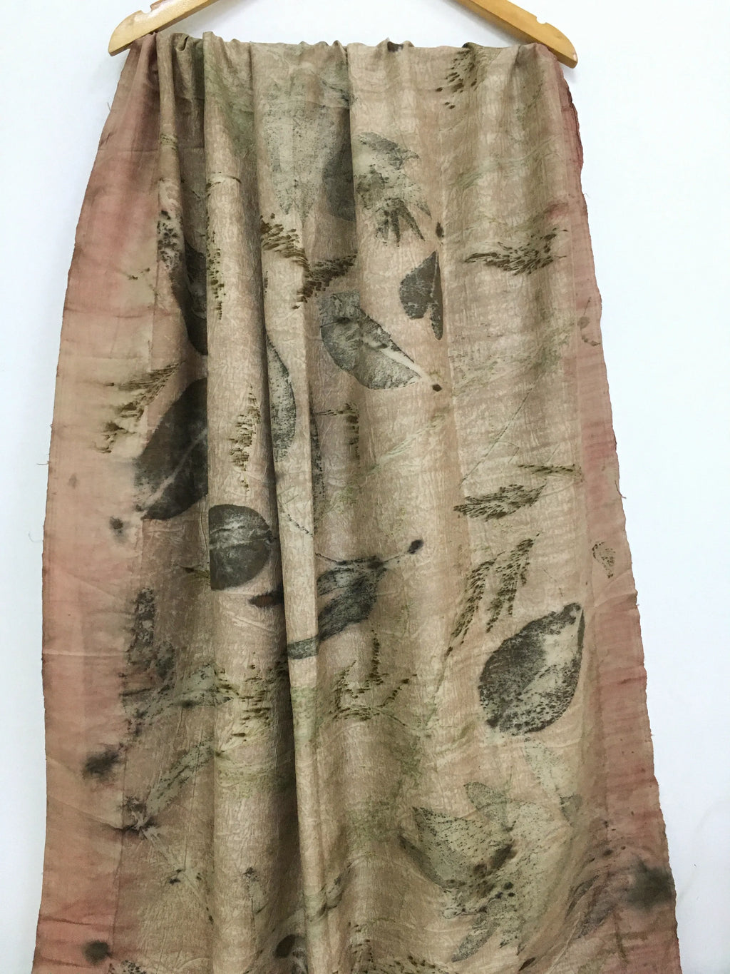 Handcrafted pure silk scarf featuring eco-printed botanical leaf patterns in earthy sage green and blush tones, created using natural dyes and sustainable eco-printing techniques.