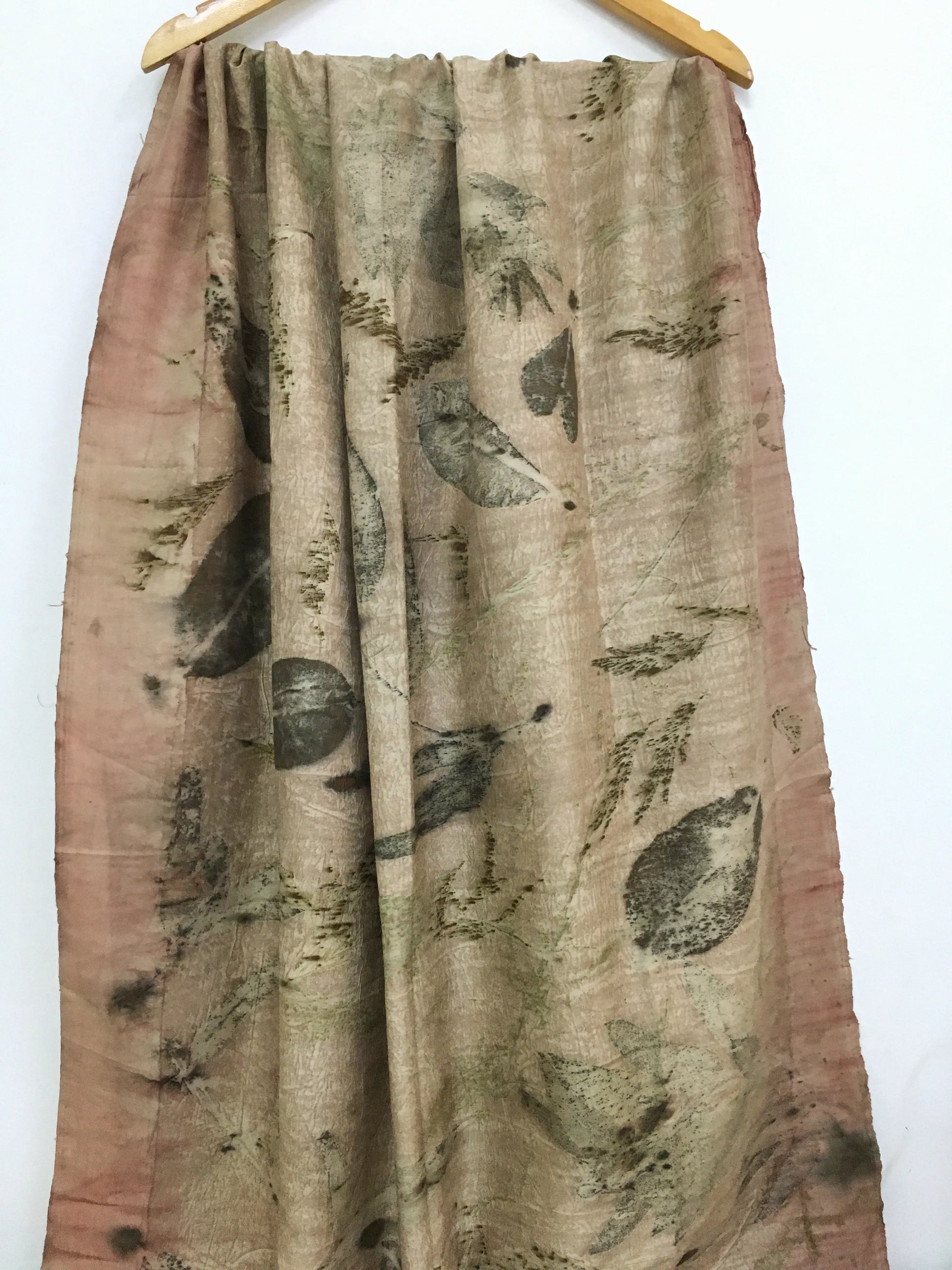 Handcrafted pure silk scarf featuring eco-printed botanical leaf patterns in earthy sage green and blush tones, created using natural dyes and sustainable eco-printing techniques.