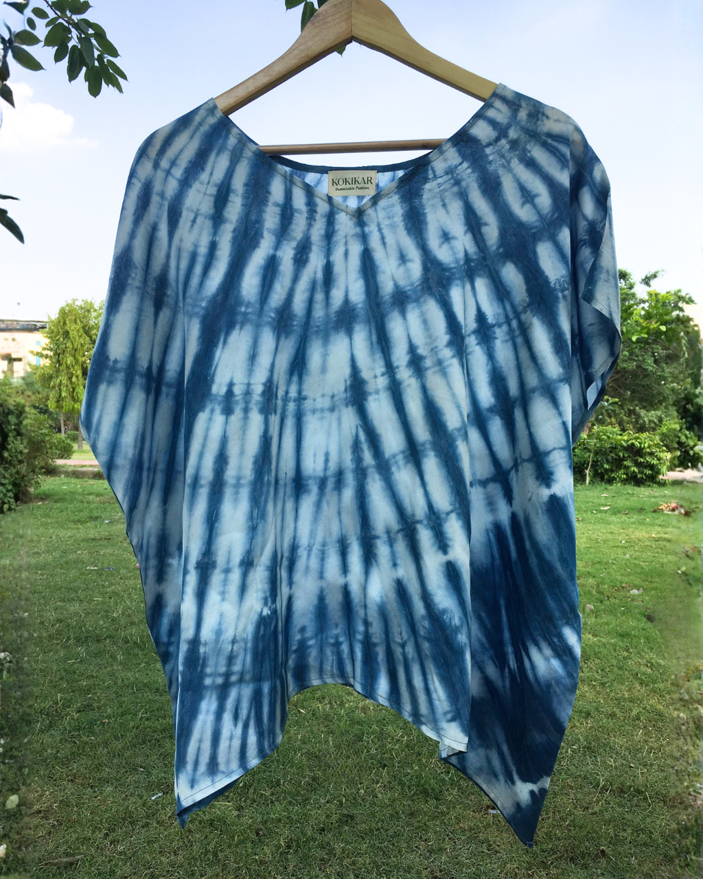 Blue shibori Kaftan Flared Top on a hanger with a natural background