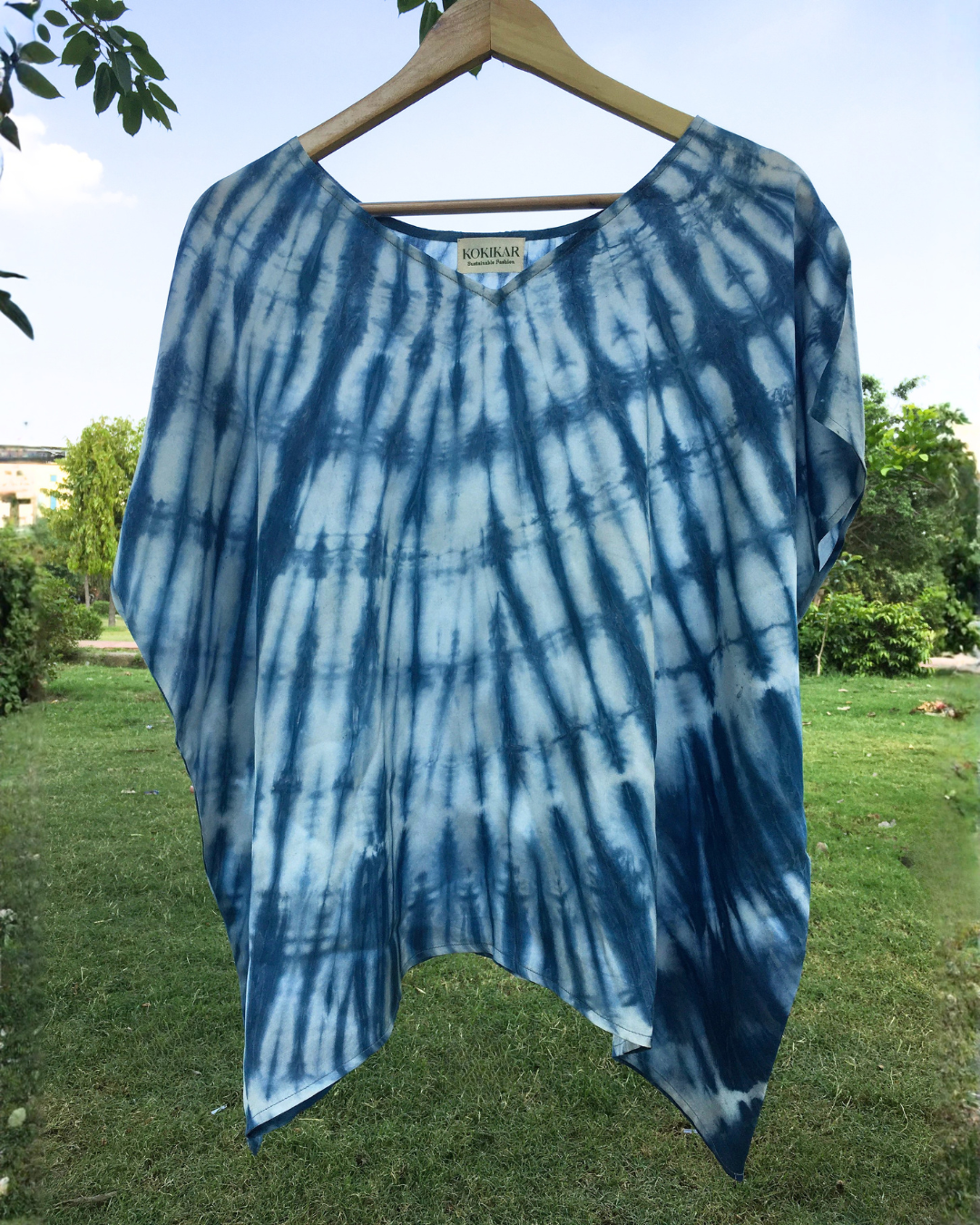 Blue shibori Kaftan Flared Top on a hanger with a natural background